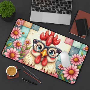 May include: A rectangular mousepad featuring a cartoon chicken wearing glasses, surrounded by pink daisies. The background has a patchwork design with pastel colors. A computer mouse and keyboard are visible.