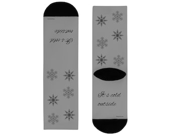 May include: A pair of gray socks with black heels and toes. The socks feature a snowflake pattern and the text "It's cold outside" in a script font. The socks are designed for winter wear.