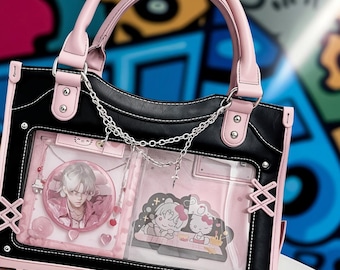 May include: Black and pink tote bag with a clear front panel displaying anime-style artwork and a silver chain. The bag has pink handles and trim, with decorative stitching and metal accents. The bag features a shoulder strap.