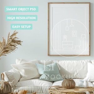 May include: A framed, blank art print mockup with a light wood frame hangs above a white sofa with decorative pillows. The text "SMART OBJECT PSD", "HIGH RESOLUTION", and "EASY SETUP" are displayed on the wall. A woven basket and dried plants are in the foreground.