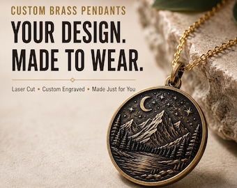 May include: A round brass pendant on a gold-toned chain featuring an engraved mountain landscape with a crescent moon, stars, and pine trees. Text reads: CUSTOM BRASS PENDANTS, YOUR DESIGN. MADE TO WEAR., Laser Cut, Custom Engraved, Made Just for You.