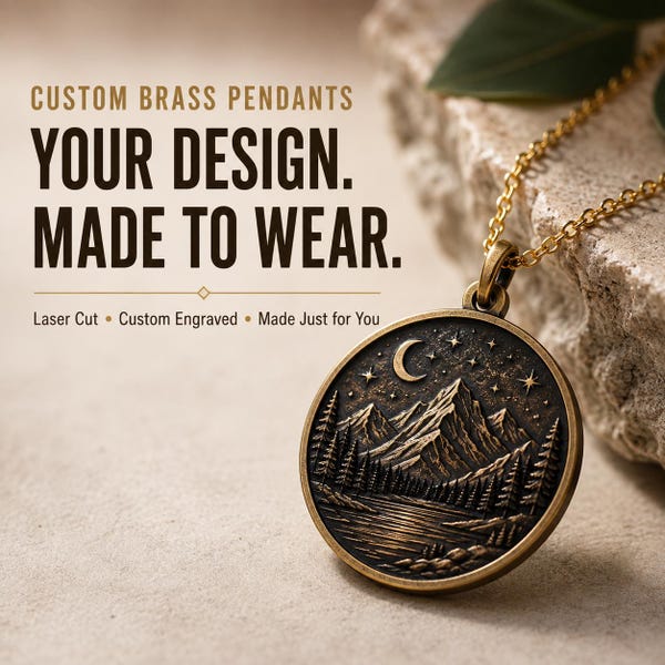 May include: A round brass pendant on a gold-toned chain featuring an engraved mountain landscape with a crescent moon, stars, and pine trees. Text reads: CUSTOM BRASS PENDANTS, YOUR DESIGN. MADE TO WEAR., Laser Cut, Custom Engraved, Made Just for You.