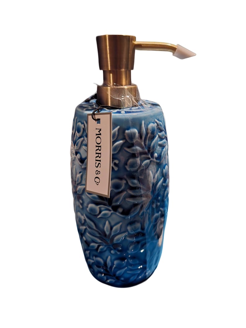 Puede incluir: Un dispensador de jab&oacute;n de cer&aacute;mica azul con un dise&ntilde;o floral y una bomba dorada. El dispensador tiene una etiqueta que dice "MORRIS & Co."