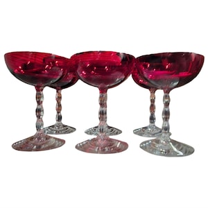 Puede incluir: Juego de seis copas de champán de color rojo rubí. Cada copa presenta un cuenco redondo, un tallo retorcido y una base ancha y plana. Las copas son de cristal transparente y son ideales para servir champán o cócteles.