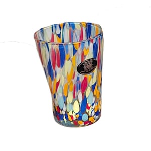 May include: A colorful glass vase with an irregular shape. The vase is decorated with a pattern of blue, red, yellow, and white teardrop shapes. A black sticker is affixed to the side of the vase.