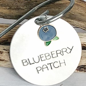 May include: A silver metal garden marker with a blueberry design and the text "Blueberry Patch".