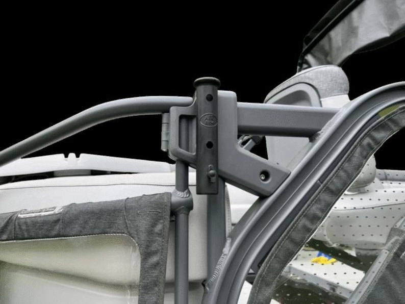 May include: Close-up of a gray metal stroller frame with a black background. The frame has a curved handlebar and a connecting bracket. The stroller's fabric is visible on the sides.