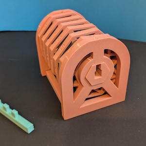 May include: A coral-colored, arched structure with a geometric design, possibly a decorative element or a component of a larger structure. A small, light green, rectangular piece with evenly spaced protrusions is also present.