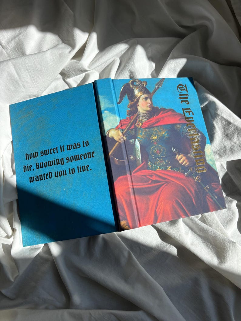 May include: A hardcover book with a bright blue cover featuring a painting of a figure in a winged helmet and red cloak holding a spear. The text on the front reads The Everlasting and the back cover text reads how sweet it was to die, knowing someone wanted you to live.
