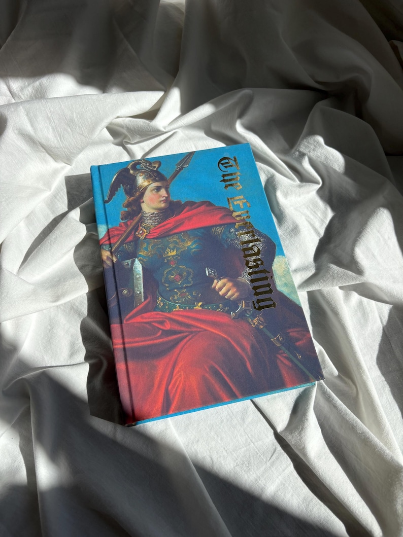May include: A hardcover book titled The Everlasting featuring a vibrant illustration of a figure in medieval armor with a winged helmet and a red cloak, holding a spear and sword against a bright blue sky background with detailed gold lettering.