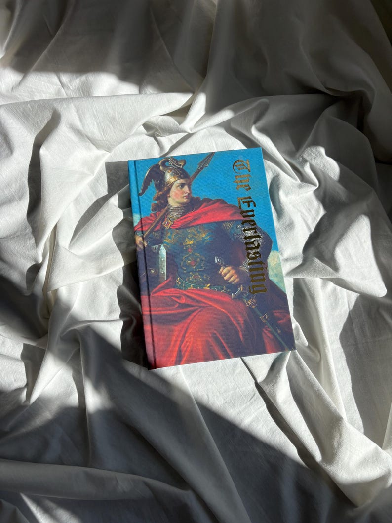 May include: A hardcover book titled The Everlasting featuring a vibrant illustration of a figure in ornate armor and a flowing red cloak, holding a spear and sword against a blue sky background, with gold lettering on the front cover.