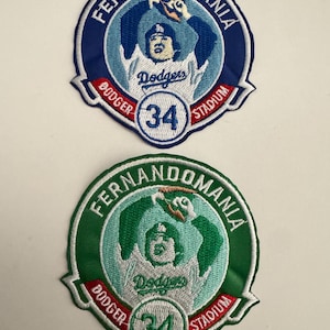May include: Two embroidered patches featuring the text "FERNANDOMANIA" in a circular design. One patch is blue and white, the other is green and white. Both patches have the text "Dodgers" and the number "34".