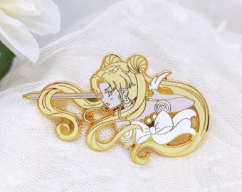 May include: Gold-colored enamel pin featuring a side profile of a character with long, flowing blonde hair and a sword. The pin has white and light blue accents, with a detailed design and a polished finish. The pin is likely a collectible item or accessory.