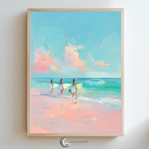 May include: A framed art print depicts three figures carrying surfboards on a beach. The artwork features a pastel color palette of pink, blue, and turquoise, with a light wooden frame. The sky is a light blue with pink clouds.