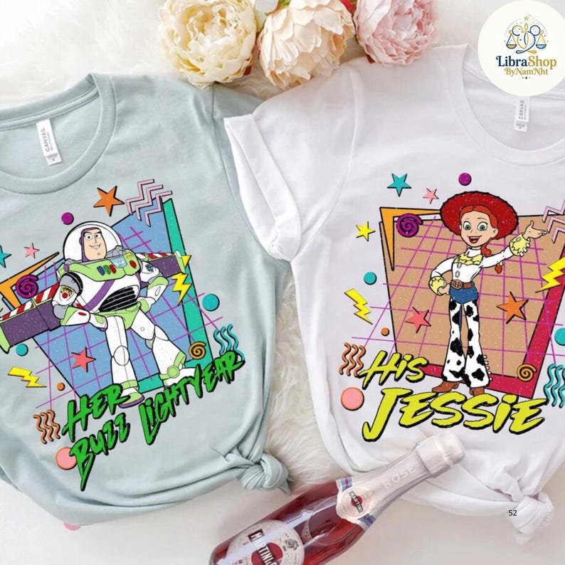 May include: Two t-shirts, one light blue and one white, featuring cartoon characters Buzz Lightyear and Jessie. The light blue shirt says "Her Buzz Lightyear" and the white shirt says "His Jessie". Both shirts have colorful retro graphics.