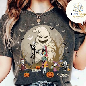 Może przedstawiać: Ciemnoszara koszulka z grafiką o tematyce Halloween. Projekt przedstawia Jacka Skellingtona, Sally i Oogie Boogie przed pełnią księżyca. Nietoperze, dynie i inne postacie dopełniają scenę. Koszulka ma efekt vintage.