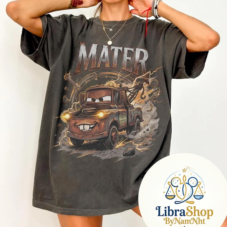 May include: Dark gray t-shirt featuring Mater from the movie Cars. The graphic shows Mater with the word "MATER" above him. The design includes lightning bolts and a detailed background. The shirt has a vintage, worn look.