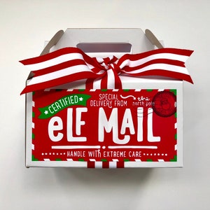 May include: A white gift box with a red and white striped ribbon. The box has a red label with the words "ELF MAIL" in white, and "HANDLE WITH EXTREME CARE". The label also says "CERTIFIED" and "SPECIAL DELIVERY FROM the north pole".