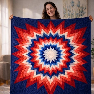 May include: A colourful quilt with a starburst design in red, white, and blue. The quilt has a central white star, encircled by layers of red, white, and blue points, set against a dark blue backdrop. A decorative textile for the home.