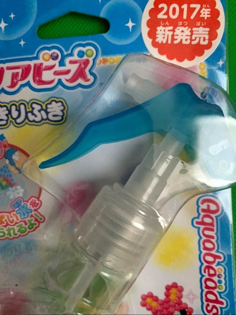 May include: A clear plastic Aquabeads spray bottle with a blue trigger. The packaging is blue and green with Japanese text and the Aquabeads logo. The package also has a red and white sticker that says "2017 New Release".