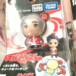 May include: A packaged Takara Tomy figure featuring a small, stylized character in a red jacket and a clear bubble. The packaging includes Japanese text and a small illustration of a yellow character with red and orange accents.