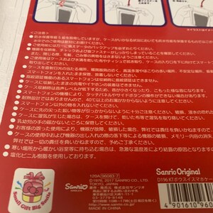 Pode incluir: Embalagem vermelha e branca para uma capa de smartphone, com o logotipo da Sanrio e texto em japon&ecirc;s. A embalagem inclui ilustra&ccedil;&otilde;es e avisos. A capa foi projetada para proteger o telefone.