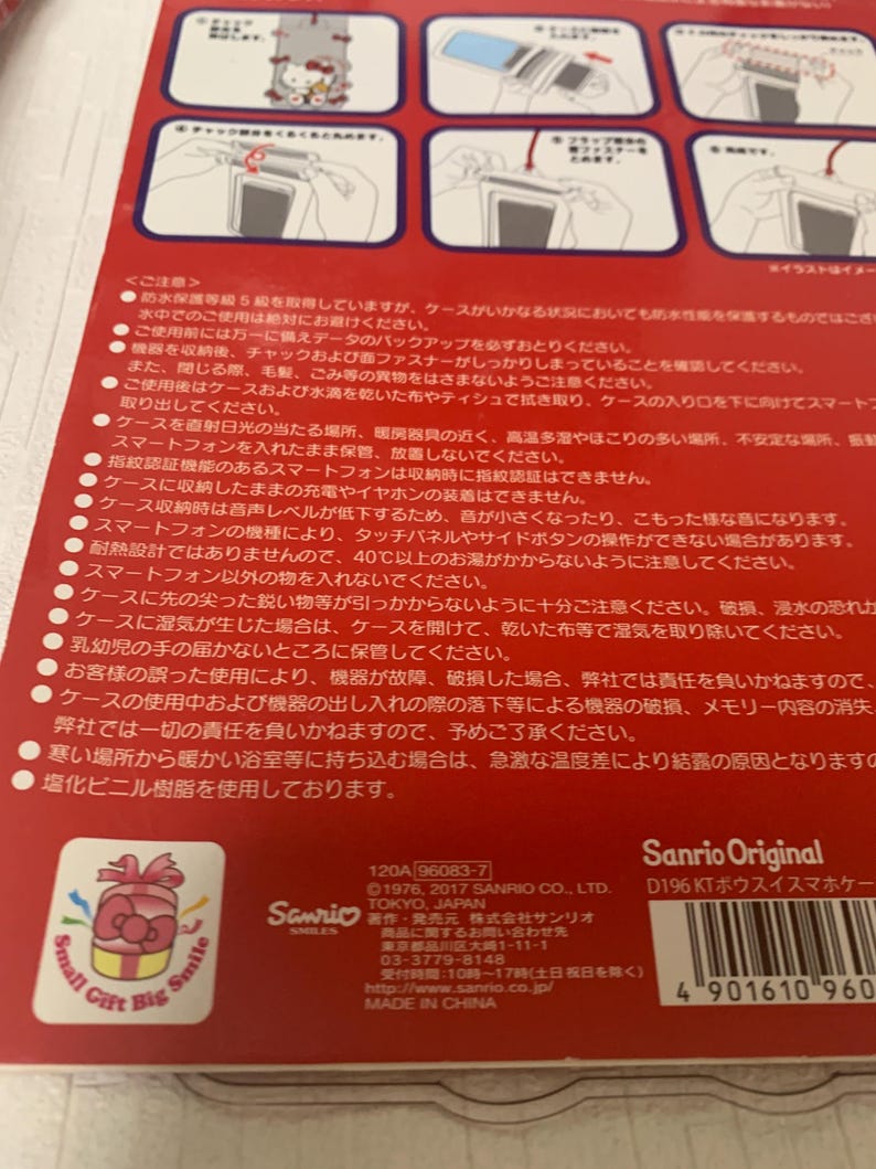 Pode incluir: Embalagem vermelha e branca para uma capa de smartphone, com o logotipo da Sanrio e texto em japon&ecirc;s. A embalagem inclui ilustra&ccedil;&otilde;es e avisos. A capa foi projetada para proteger o telefone.