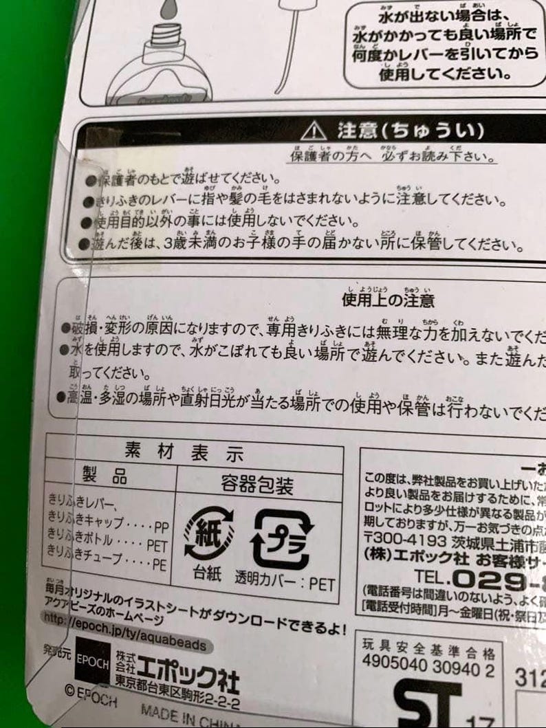 May include: A product information label in Japanese. The label includes warnings, usage instructions, and material details. The packaging materials are listed as paper and plastic. The label also features the manufacturer's logo and website.