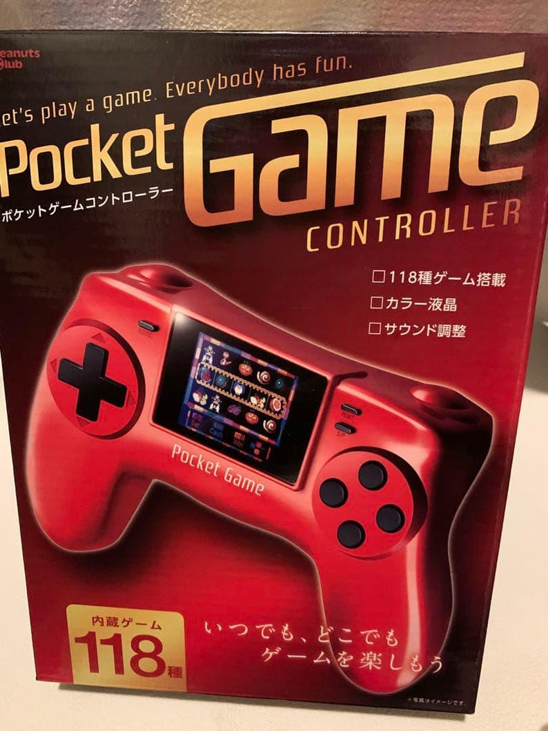 Pode incluir: Controlador Pocket Game vermelho com um pequeno ecr&atilde; que exibe gr&aacute;ficos de jogos. O controlador tem um D-pad em forma de cruz, bot&otilde;es e o texto "Pocket Game" na frente. A caixa diz "Let's play a game. Everybody has fun."