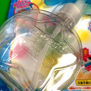 May include: A clear plastic spray bottle with a white nozzle and a clear, rounded container. The bottle is partially filled with a colorful liquid. Japanese text is visible on the packaging.