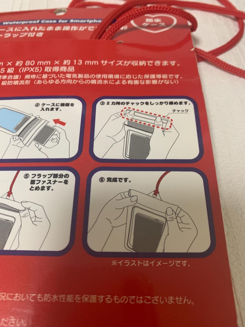 Pode incluir: Capa de smartphone &agrave; prova d'&aacute;gua vermelha com cord&atilde;o. A embalagem mostra diagramas de uso. A capa pode conter dispositivos de at&eacute; 8 cm x 1,3 cm. O texto na embalagem est&aacute; em japon&ecirc;s.