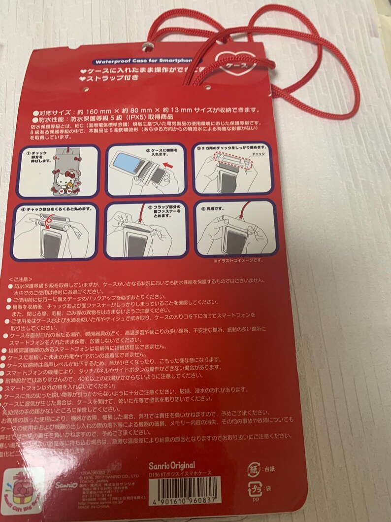 Pode incluir: Capa de smartphone &agrave; prova d'&aacute;gua vermelha com etiqueta em forma de cora&ccedil;&atilde;o e cord&atilde;o vermelho. A embalagem apresenta texto e ilustra&ccedil;&otilde;es japonesas, incluindo um design Hello Kitty. A capa &eacute; projetada para telefones de at&eacute; 16 cm x 8 cm x 1,3 cm.