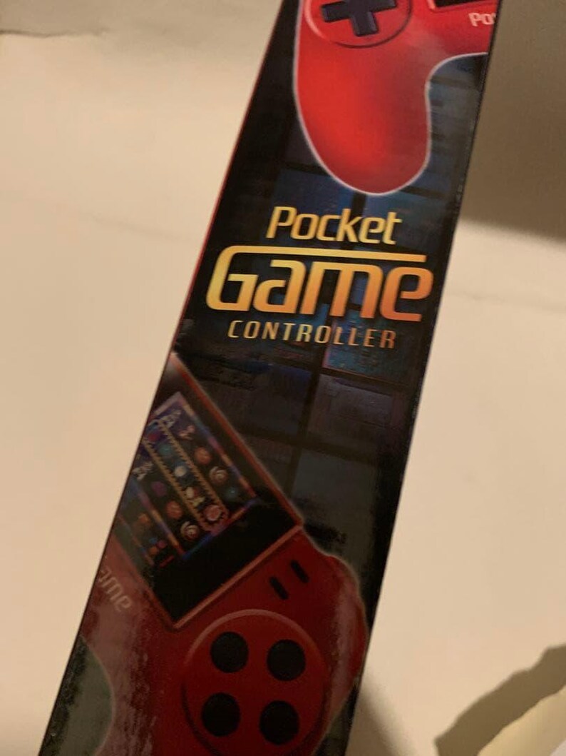 Pode incluir: Uma caixa preta e vermelha do Pocket Game Controller. A caixa apresenta um gr&aacute;fico de controle de jogo vermelho na parte superior e um gr&aacute;fico menor de um console de jogo. As palavras "Pocket Game Controller" s&atilde;o em ouro e branco.