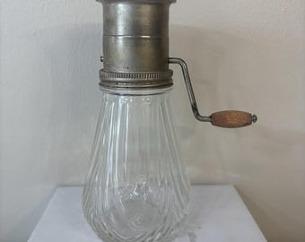 Molinillo de nueces vintage con tarro de cristal transparente acanalado y manivela de madera.
