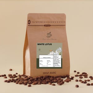 Könnte beinhalten: Ein brauner Papiersack mit "White Lotus" Kaffee aus einer einzigen Herkunft, mit einem Etikett, das die Herkunft und Röstung beschreibt. Der Beutel ist mit einem Reißverschluss verschlossen und enthält 340g Kaffee. Kaffeebohnen sind verstreut.