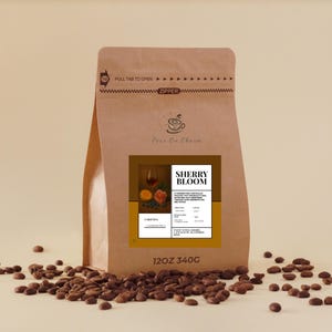May include: A brown paper bag of coffee beans, labelled "Sherry Bloom". The bag has a zipper seal and contains 340g of coffee. Coffee beans are scattered around the base of the bag. The bag also has the text "Pour On Charm".
