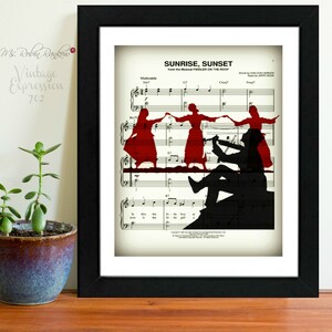 May include: A framed print of sheet music with the title "Sunrise, Sunset" from the musical "Fiddler on the Roof". The music is overlaid with a silhouette of three people dancing.