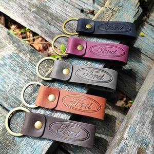 Puede incluir: Cinco llaveros de cuero en varios colores: negro, burdeos, gris, marrón y marrón oscuro. Cada llavero presenta el logotipo Ford en relieve y un anillo y remache color latón.