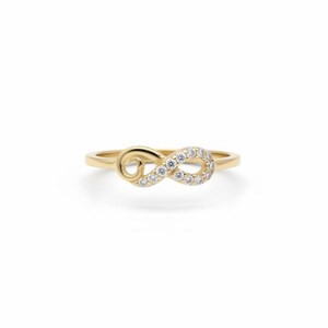 Pu&ograve; includere: Anello dorato con design a simbolo dell'infinito. Il simbolo dell'infinito &egrave; incastonato con piccole pietre preziose trasparenti. L'anello ha una fascia liscia e un aspetto delicato. Un gioiello elegante.