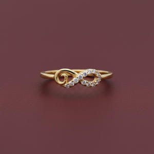 Pu&ograve; includere: Anello dorato a forma di infinito, ornato da piccoli diamanti e un motivo a spirale. Il gioiello &egrave; posto su uno sfondo rosso scuro, che ne esalta l'elegante design.