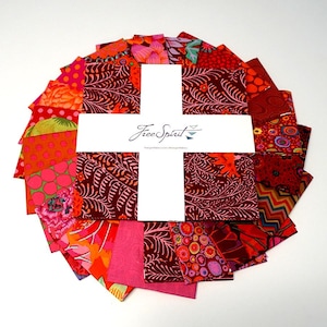 May include: A collection of colorful fabric squares arranged in a circular pattern. The fabrics feature various patterns in shades of red, pink, and orange. A white card with the text "Free Spirit" is in the center.
