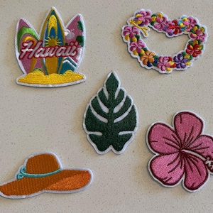 Könnte beinhalten: Gestickte Aufnäher mit tropischem Thema. Enthält ein Surfbrett mit dem Text "Hawaii", ein Blumenherz, ein grünes Blatt, eine rosa Hibiskusblüte und einen orangefarbenen Sonnenhut. Jeder Aufnäher hat einen weißen Rand.