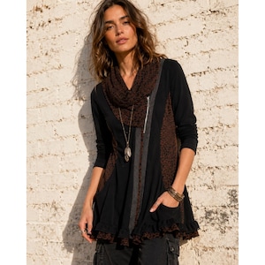 May include: Black long-sleeved tunic with a brown leopard print panel and a cowl neck. The tunic features a zipper, a gray stripe, and a ruffled hem. A long gold necklace and bracelets are visible.