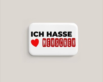 May include: A white rectangular button with the German phrase "ICH HASSE MENSCHEN" in black and red text. A red heart graphic is to the left of the text. The button is on a light gray background.