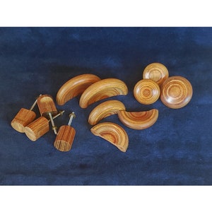 May include: A set of wooden cabinet knobs in various shapes and sizes. The knobs are made of wood with a natural grain pattern and have a warm brown color.