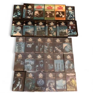 May include: A collection of thirty VHS tapes from The Outer Limits television series, arranged in five rows. Each rectangular case features distinct black and white or color graphic artwork, episode titles, and the series logo printed on the front.