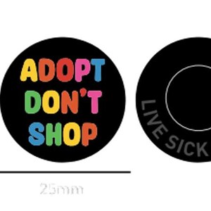 May include: Two 2.5 inch round black buttons. One button says "Adopt Don't Shop" in rainbow letters. The other button says "Live Sick Die Ill" in gray letters.