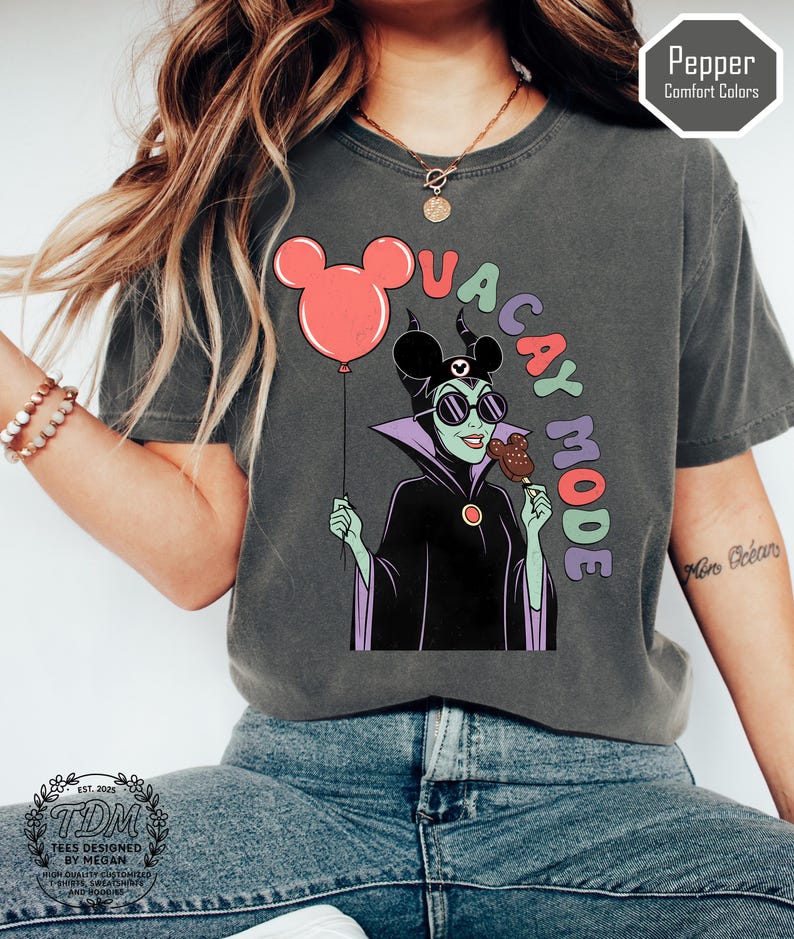 K&ouml;nnte beinhalten: Dunkelgraues T-Shirt mit einem Cartoon von Maleficent, die einen Mickey Mouse-Ballon und ein Eis h&auml;lt. Der Text "VACAY MODE" ist &uuml;ber der Figur angeordnet. Das Shirt tr&auml;gt den Text "Pepper Comfort Colors" und "TDM Tees Designed by Megan".