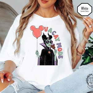 K&ouml;nnte beinhalten: Wei&szlig;es T-Shirt mit einer Grafik eines Zeichentrick-B&ouml;sewichts, der einen Mickey-Mouse-Ballon und ein Eis h&auml;lt. Der Text "VACAY MODE" ist um die Figur herum angeordnet. Das Shirt hat eine lockere Passform und ist mit "Comfort Colors" gekennzeichnet.