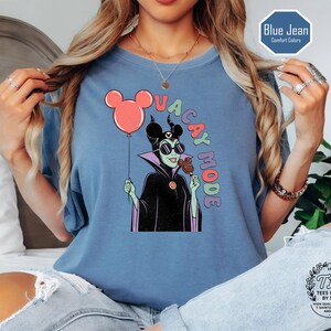 K&ouml;nnte beinhalten: Blaues kurz&auml;rmeliges T-Shirt mit einer Comicfigur, die einen Ballon und Eis h&auml;lt, mit den Worten "VACAY MODE". Das Shirt ist blau und tr&auml;gt den Aufdruck "Blue Jean Comfort Colors".
